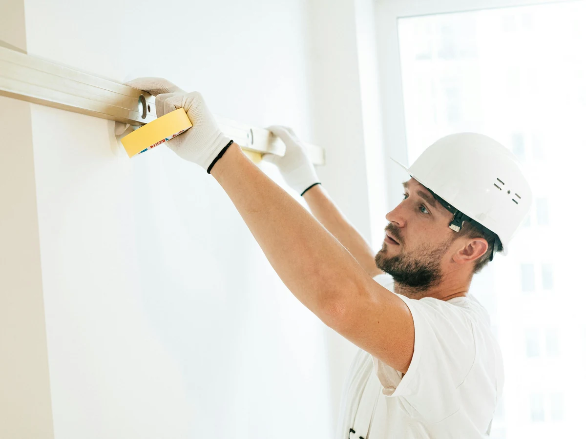 Decorator sanding ceiling in preparation for painting in Bridgend home